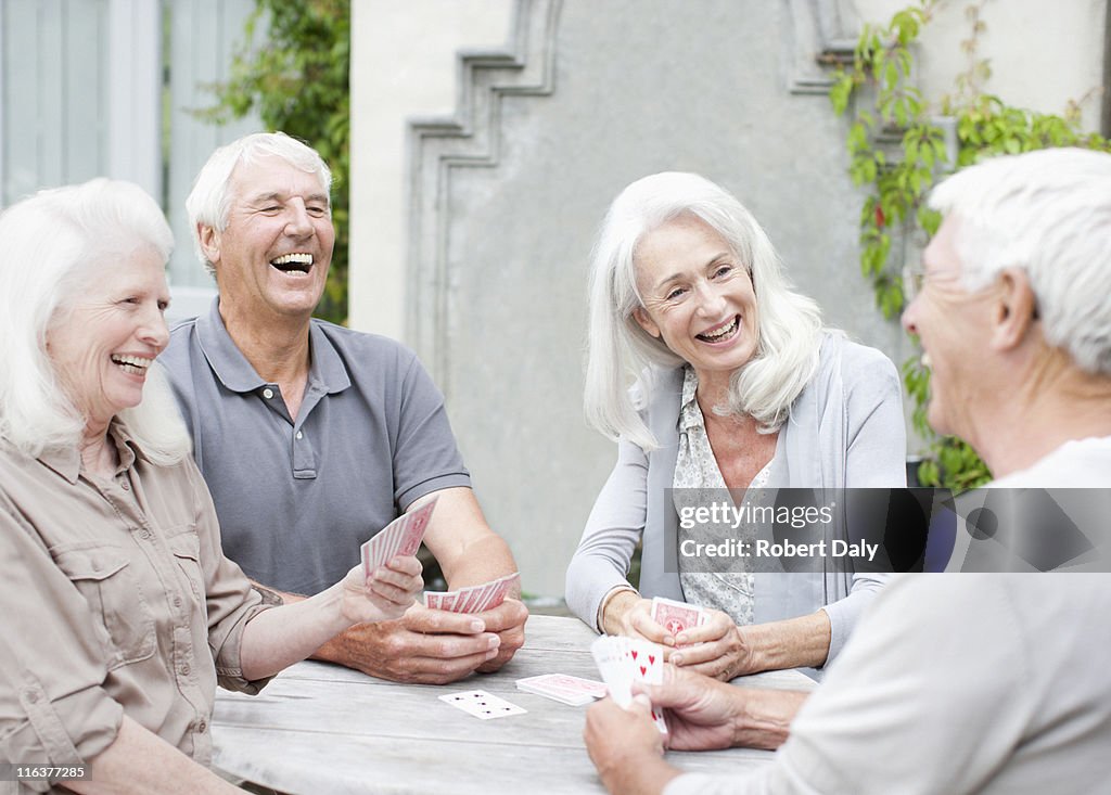 Senior couples playing cards on patio