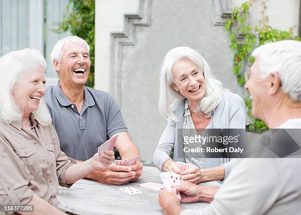 senior couples playing cards on patio - baby boomer stock pictures, royalty-free photos & images