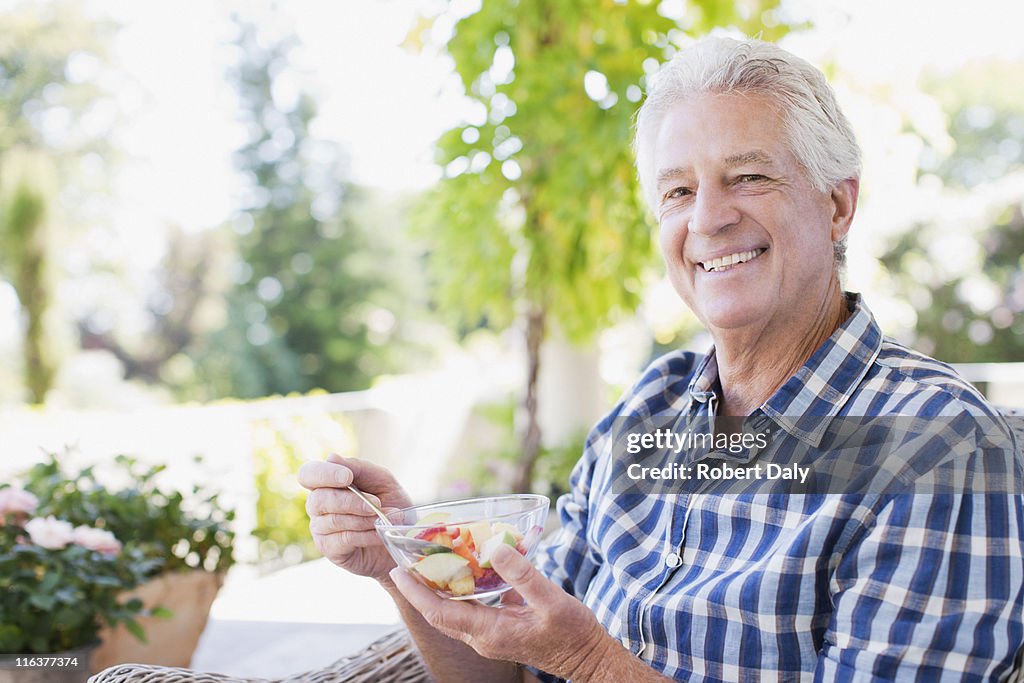 Senior man essen Gemüse auf dem patio