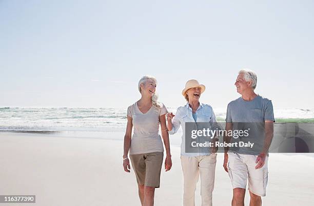 senior friends walking on beach - adult sky lady smile stock pictures, royalty-free photos & images