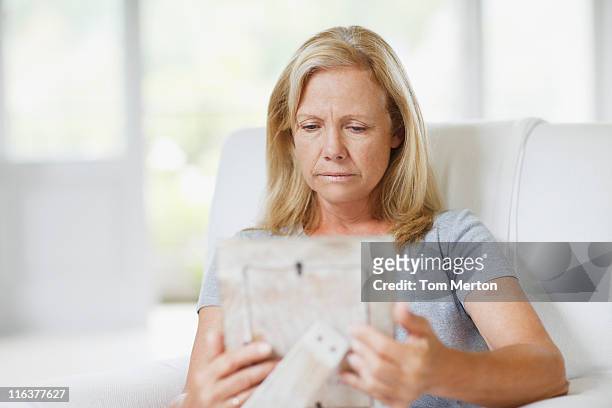frowning woman looking at picture frame - blank frame stockfoto's en -beelden