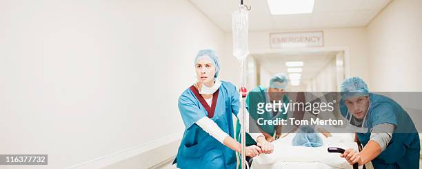 doctors pushing patient on gurney down hospital corridor - emergencies and disasters stock pictures, royalty-free photos & images