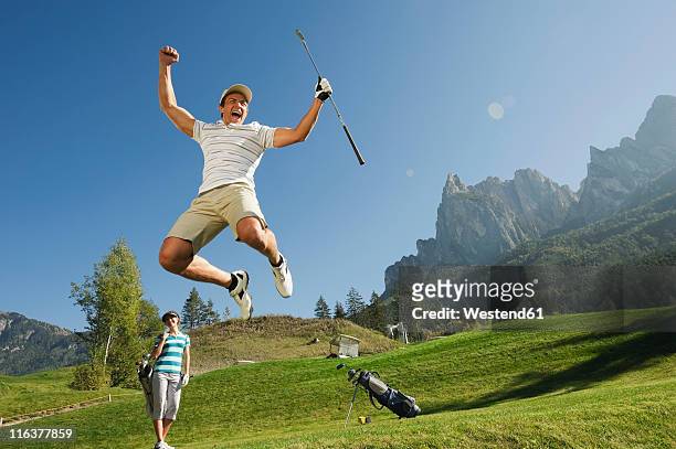 italy, kastelruth, mid adult couple on golf course - golf short iron stock pictures, royalty-free photos & images