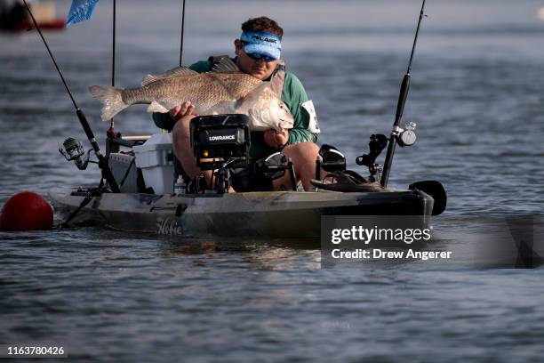 Fisherman hauls in a bull redfish while competing in the Ride the Bull Kayak Tournament in the waters between Caminada Bay and the Gulf of Mexico on...