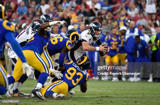 Quarterback Kevin Hogan of the Denver Broncos is sacked by defensive tackle Marquise Copeland and linebacker Landis Durham of the Los Angeles Rams...