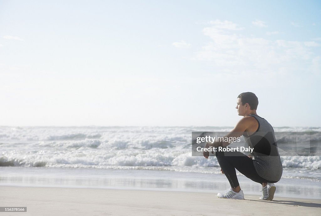 Homme Accroupi sur la plage