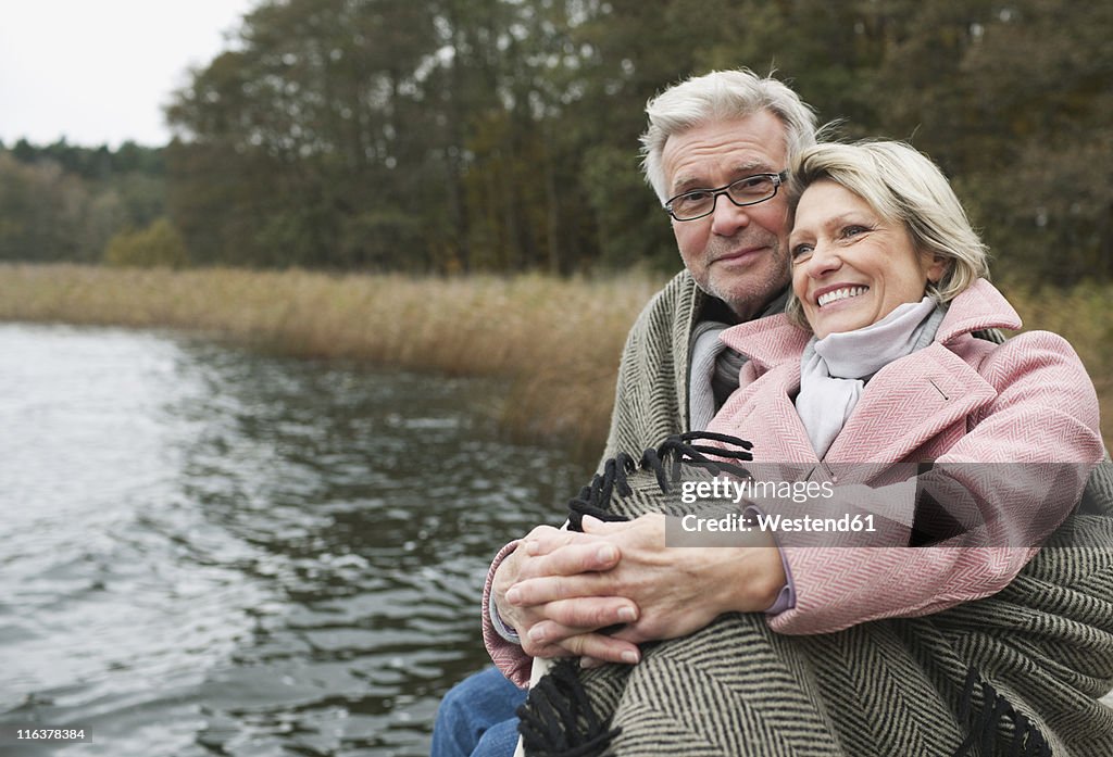 Germany, Kratzeburg, Senior couple sitting on boardwalk, smiling