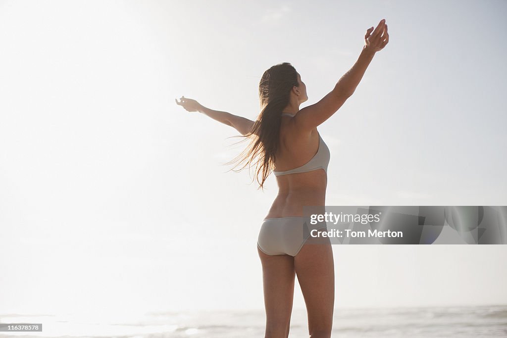 Frau mit ausgestreckten Armen am Strand