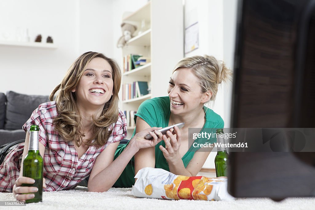 Germany, Bavaria, Munich, Young friends lying on rug and watching tv