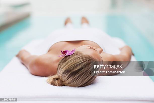 woman laying on massage table at poolside - massage table stock pictures, royalty-free photos & images