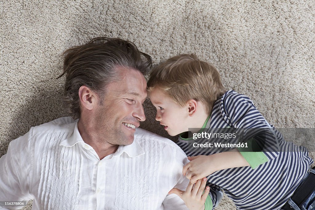 Germany, Bavaria, Munich, Father and son lying on floor