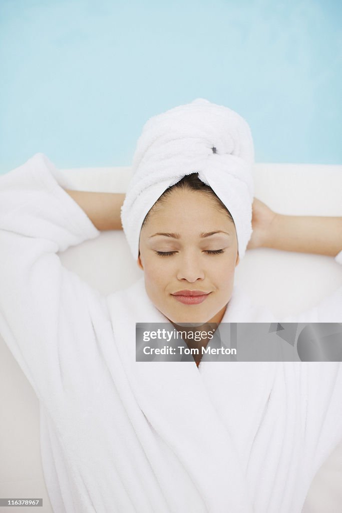 Woman with head wrapped in towel laying at poolside