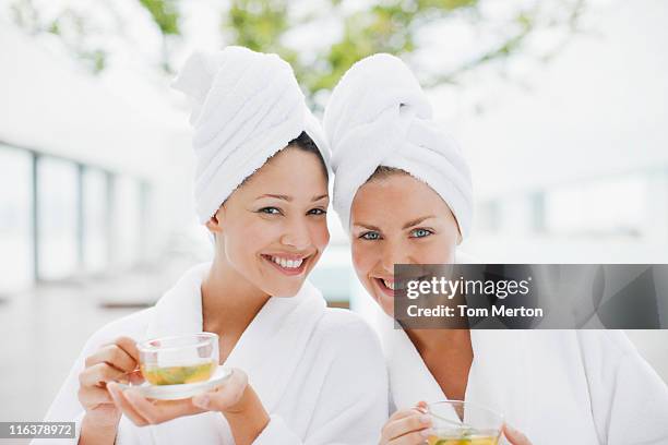 women in bathrobes drinking tea at spa - hälsosalong bildbanksfoton och bilder