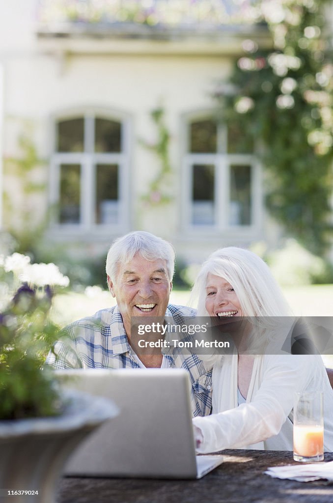 Couple Senior à l'aide d'ordinateur portable à table dans le jardin