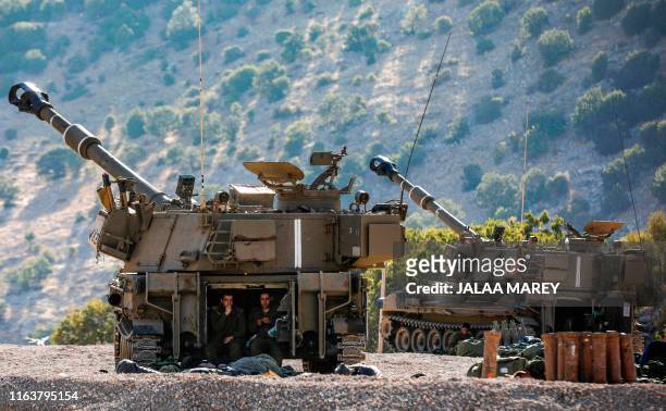 Israeli soldiers sit in the back of a self-propelled artillery gun positioned along the border with Syria in the the Israeli-annexed Golan Heights on...