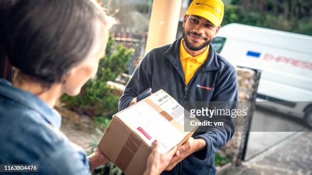 zusteller liefert paket an heimkunden - postman stock-fotos und bilder