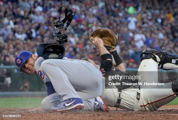 Anthony Rizzo of the Chicago Cubs scores after colliding while colliding with catcher Stephen Vogt of the San Francisco Giants in the top of the...