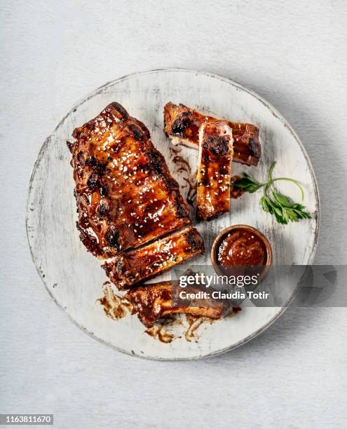 full rack of grilled barbecue ribs with barbecue sauce on a wooden cutting board on white background - plato de carne fotografías e imágenes de stock