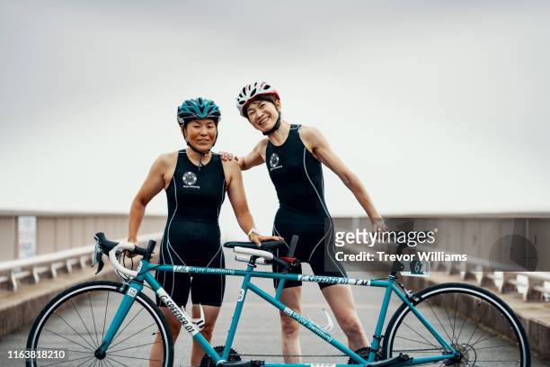 Portrait of a visually impaired female triathlete and her guide and coach with their tandem bicycle