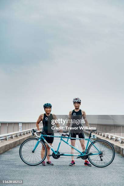 portrait of a visually impaired female triathlete and her guide and coach with their tandem bicycle - tandem bicycle stock-fotos und bilder