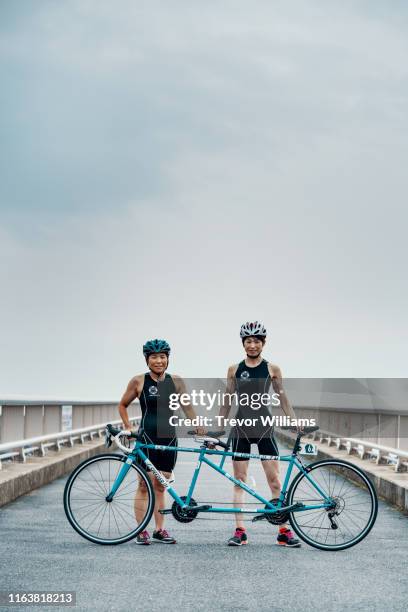 portrait of a visually impaired female triathlete and her guide and coach with their tandem bicycle - tandem bicycle foto e immagini stock