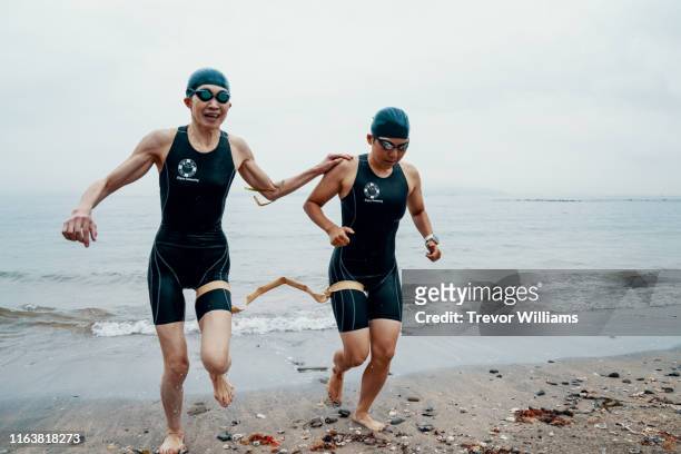 View from directly above a visually impaired female triathlete swimming in the ocean with her guide
