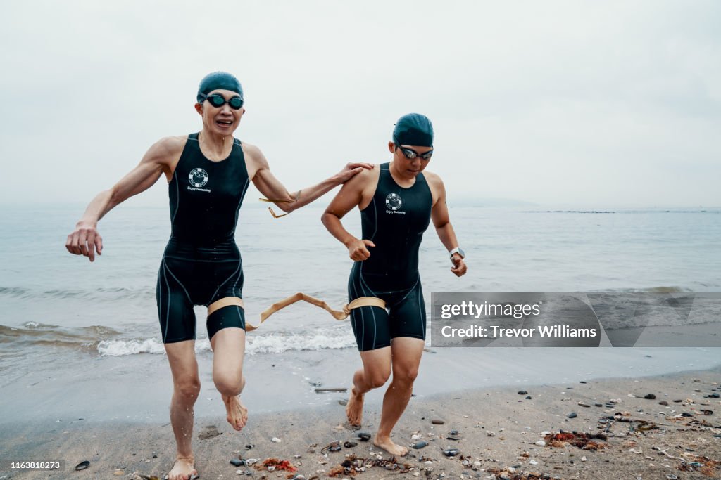 View from directly above a visually impaired female triathlete swimming in the ocean with her guide
