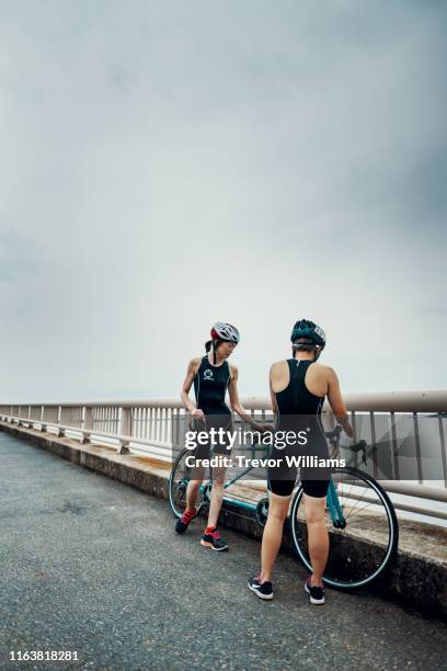 Visually impaired female triathlete taking a break from training on a tandem bicycle together with her guide and coach