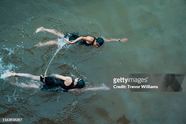 View from directly above a visually impaired female triathlete swimming in the ocean with her guide