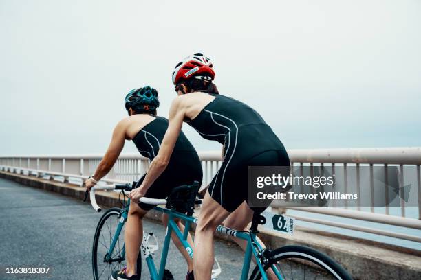 visually impaired female triathlete training together with her guide and coach on a tandem bicycle - tandem bicycle foto e immagini stock