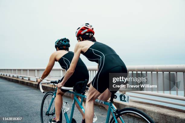 visually impaired female triathlete training together with her guide and coach on a tandem bicycle - tandem bicycle stockfoto's en -beelden