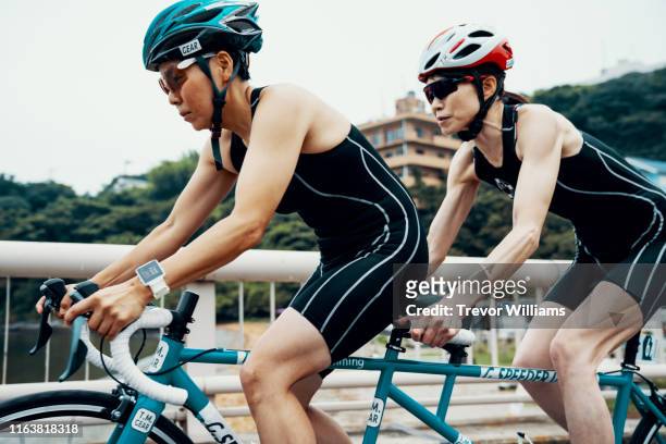 Visually impaired female triathlete training together with her guide and coach on a tandem bicycle
