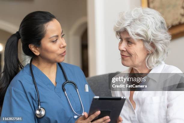 female doctor using tablet with senior patient - medicaid stock pictures, royalty-free photos & images