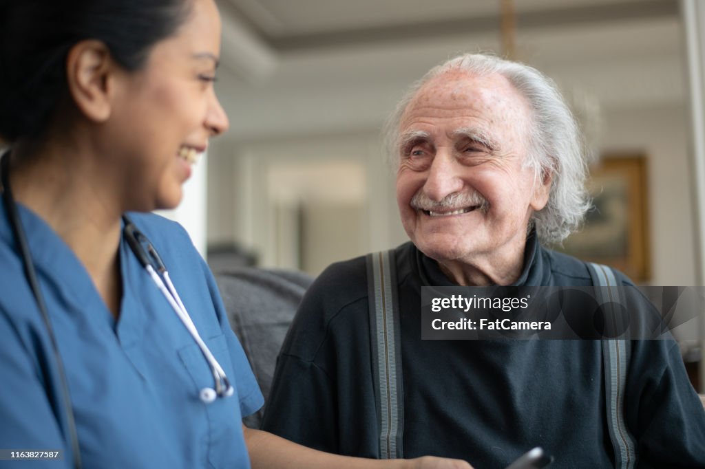Älterer Herr mit Krankenschwester während Desheimbesuch