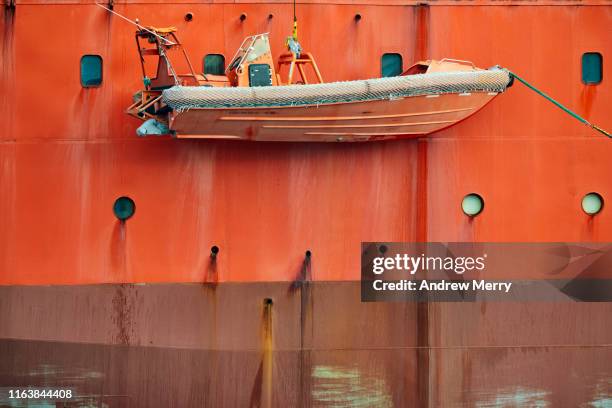 bright safety orange icebreaker ship hull and rescue dinghy lifeboat speedboat - rettungsboot stock-fotos und bilder