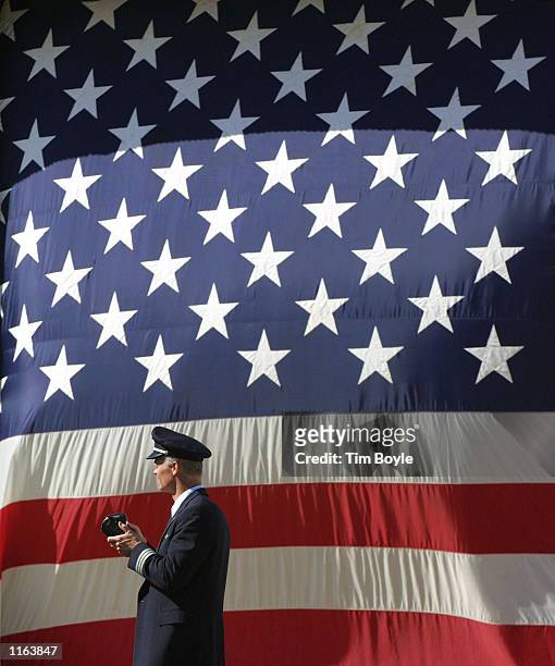 An American Airlines pilot walks in front of a large American flag after President George W. Bush spoke at a rally September 27, 2001 at O''Hare...