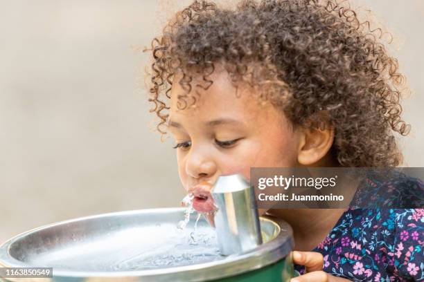 petite fille buvant de l'eau à la cour d'école - school bus stock photos et images de collection