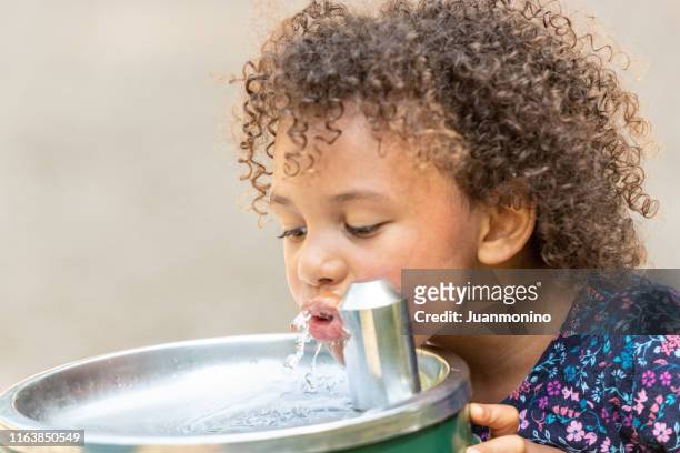 klein meisje drinkwater op het schoolplein - african girl drinking water stockfoto's en -beelden