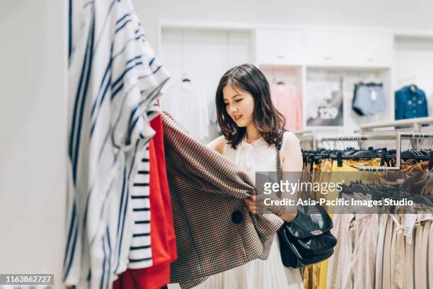 young asian woman choosing new clothes in the clothing store. - choosing outfit stock pictures, royalty-free photos & images
