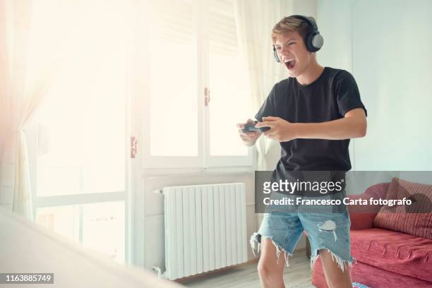 teenage boy  playing at video game - teen boy shorts stock-fotos und bilder