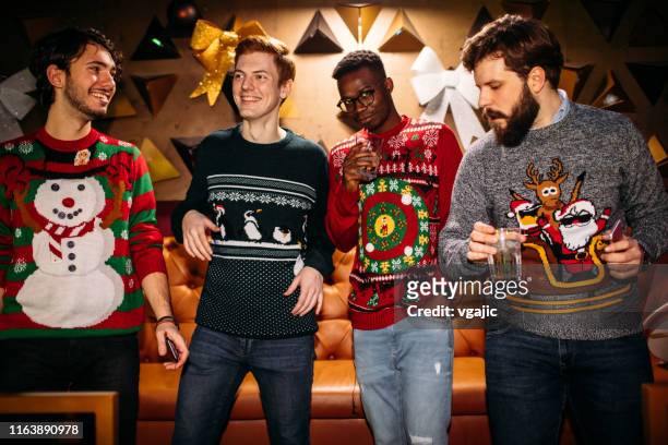 vrolijke vrienden die plezier hebben in de nachtclub. ze dragen kerst truien. - christmas jumpers stockfoto's en -beelden
