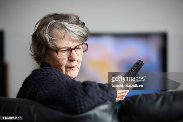 geïrriteerde senior vrouw kan geen tv-afstandsbediening werken - tv personality stockfoto's en -beelden