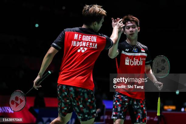 Marcus Fernaldi Gideon and Kevin Sanjaya Sukamuljo of Indonesia celebrate the victory in the Men's Doubles first round match against He Jiting and...