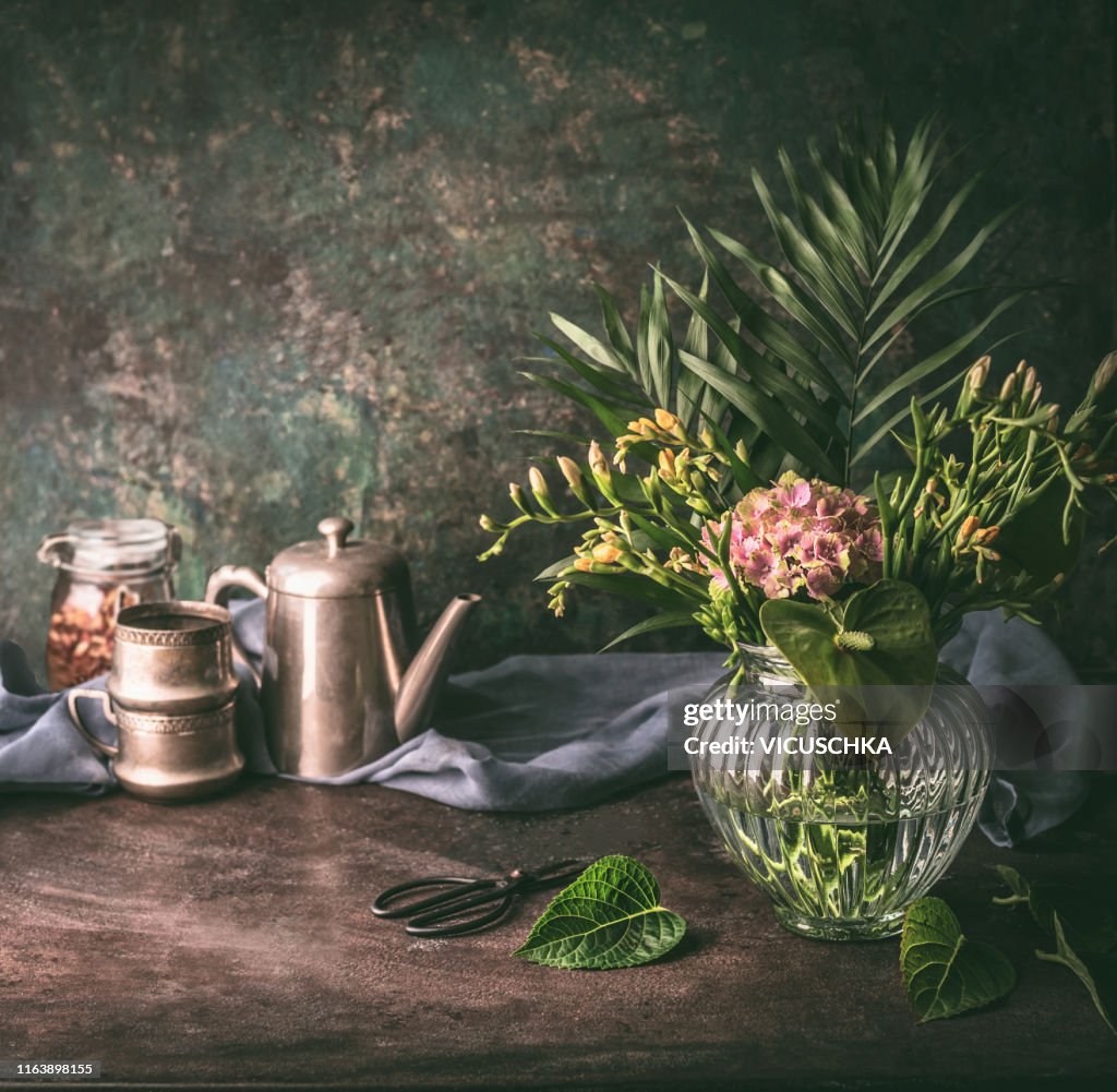 Vintage still life with glass vase , flowers and tea set