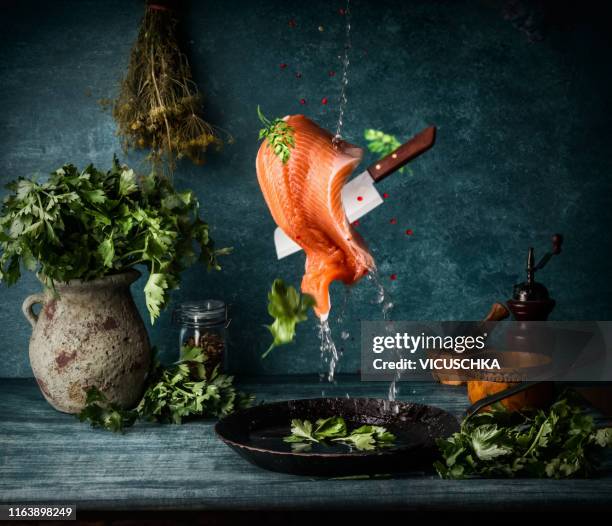 raw salmon fillet cooking preparation. flying food - food photography dark background blue stock-fotos und bilder