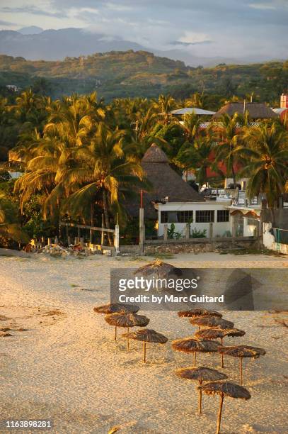 beach umbrellas and mountains, puerto escondido, oaxaca, mexico - puerto escondido stock pictures, royalty-free photos & images
