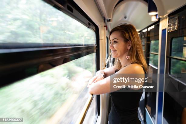 smiling woman looking out of train window - budapest train stock pictures, royalty-free photos & images