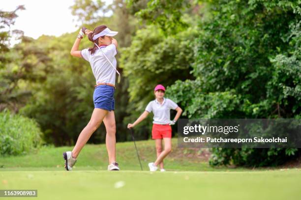 young asian golfer playing golf in golft course, healthy sport - woman on swing foto e immagini stock