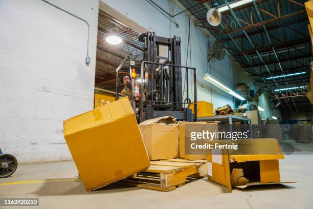 an industrial warehouse workplace safety and asset protection topic.  a forklift driver crashes into and damages merchandise by driving carelessly. - damaged box stock pictures, royalty-free photos & images