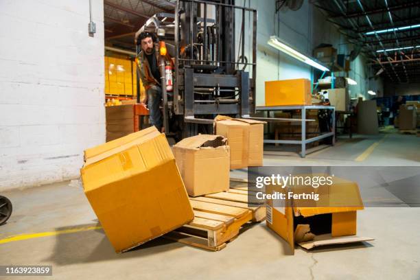 an industrial warehouse workplace safety and asset protection topic.  a forklift driver crashes into and damages merchandise by driving carelessly. - damaged box stock pictures, royalty-free photos & images